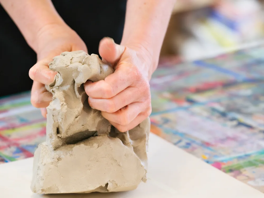 Hände kneten Ton im Atelier der Kunsttherapie-Praxis